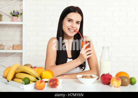 Il existe de belles femmes avec la peau pure sur son visage assis à une table et manger le petit déjeuner. Asian woman eating nourriture saine au petit-déjeuner. Des fruits, des céréales et du lait. Banque D'Images