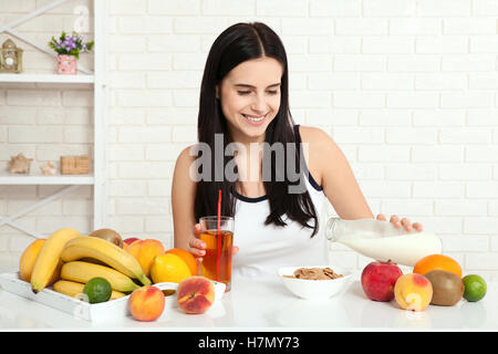 Il existe de belles femmes avec la peau pure sur son visage assis à une table et manger le petit déjeuner. Asian woman eating nourriture saine au petit-déjeuner. Des fruits, des céréales et du lait. Banque D'Images