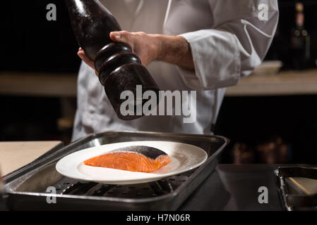 Sel concentré chef putting sur le pavé de saumon Banque D'Images