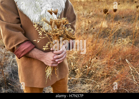 Vintage concept avec un homme tenant un bouquet de fleurs sèches Banque D'Images