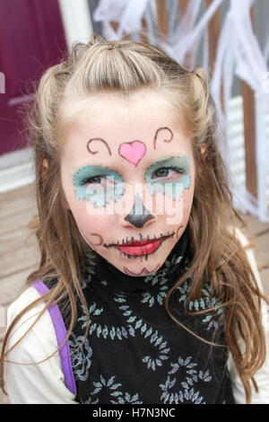 Jeune fille avec crâne en sucre maquillage halloween peint sur son visage assis sur les marches de bois Banque D'Images