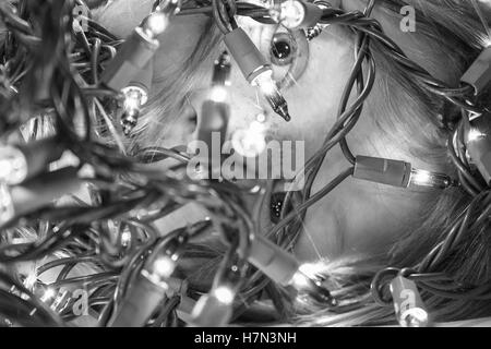 Close up of child peeking through lumières de Noël, noir et blanc Banque D'Images