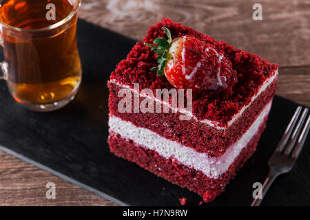 Tranche de gâteau de velours rouge avec glaçage blanc est garnie de fraises close up Banque D'Images