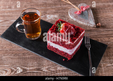 Tranche de gâteau de velours rouge avec glaçage blanc est garnie de fraises close up Banque D'Images