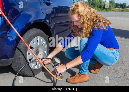 Femme pilote de vérification de la pression d'air l'extérieur des pneus de voiture Banque D'Images