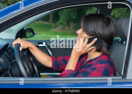 Femme européenne driving car phoning with mobile phone Banque D'Images