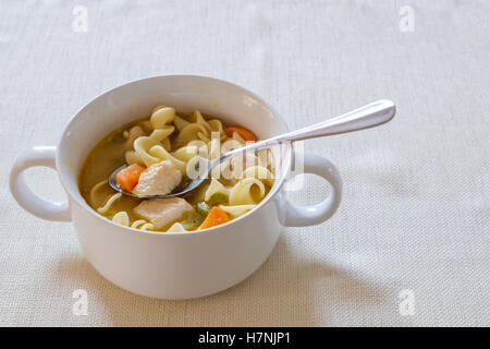Soupe poulet et nouilles faites maison avec des carottes et céleri servi dans un bol blanc. Banque D'Images