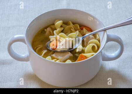 Soupe poulet et nouilles faites maison, de confort, de nourriture contenant des carottes et le céleri, servi dans un bol blanc. Libre. Banque D'Images