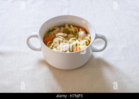 Soupe poulet et nouilles faites maison, de confort, de nourriture contenant des carottes et le céleri, servi dans un bol blanc. Banque D'Images
