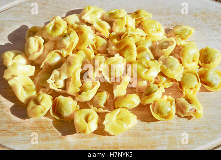 Des matières premières tomates tortellini sur une planche en bois Banque D'Images