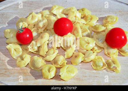 Tortellini cru avec tomates Pachino sur une planche en bois Banque D'Images