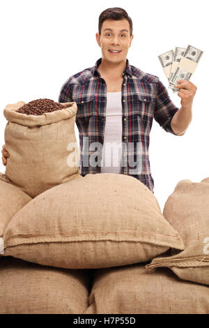 Jeune agriculteur avec sacs de toile remplis de grains de café de la détention de monnaie bundles isolé sur fond blanc Banque D'Images