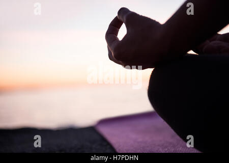 Mid section of woman performing yoga on beach Banque D'Images