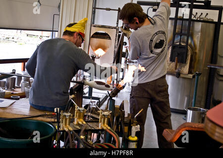 Deux hommes travaillent dans un magasin, faire verre soufflé au chalumeau et l'équipement de fabrication du verre. Banque D'Images
