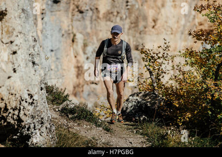 Homme d'âge moyen s'exécute sur un sentier avec sac à dos running marathon de montagne au cours de la Crimée Banque D'Images