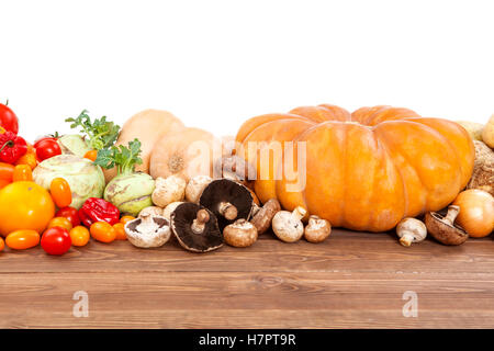 La récolte de légumes d'automne sur table en bois, fond blanc. Potiron, courgette, pommes de terre, oignons et autres légumes. Banque D'Images