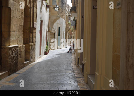 Un résident local était assis dans l'embrasure d'une rue étroite à Rabat, Malte. Banque D'Images