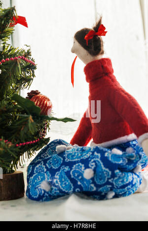 Poupée en tissu souple près d'un arbre de Noël avec des cadeaux. Banque D'Images