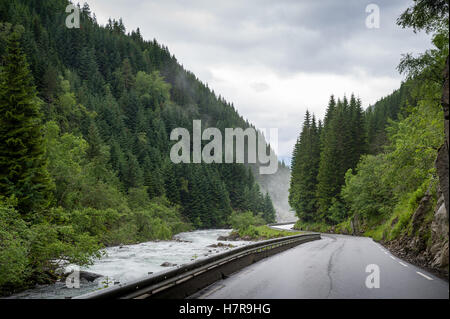 Route norvégienne entre fleuve et montagnes. Banque D'Images