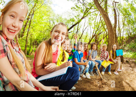 Rire les enfants assis sur un log dans le camp d'été Banque D'Images