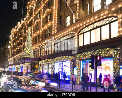 HARRODS CHRISTMAS TREE SHOPPING SHOPPERS LONDON Harrods grand magasin au crépuscule avec des lumières de Noël de la foule de shopping et de passage de voitures Knightsbridge Londres SW1 Banque D'Images