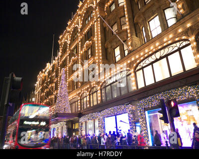 Les acheteurs de Noël lumières HARRODS LONDRES FLOU Harrods au crépuscule avec des lumières de Noël shopping foules et passant red bus Knightsbridge Londres SW1 Banque D'Images