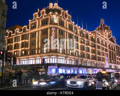 Les acheteurs de Noël lumières FLOU TRAFFIC Harrods au crépuscule avec des lumières de Noël shoppers et passant le trafic trouble Knightsbridge Londres SW1 Banque D'Images