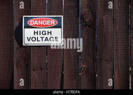 Panneau d'avertissement de tension élevée sur clôture en bois à une sous-station en Nouvelle Zélande Banque D'Images