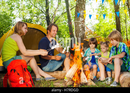 Famille heureuse le rôtissage de la guimauve sur le feu Banque D'Images