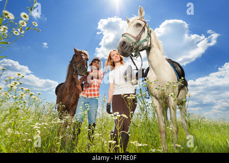 Jeune couple avec les chevaux marcher à flowery meadow Banque D'Images