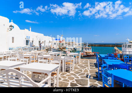 PORT DE NAOUSSA, PAROS ISLAND - 20 MAI 2016 : tables de taverne grecque typique et bâtiments dans le port de Naoussa, Paros island, Cyclades, en Grèce. Banque D'Images