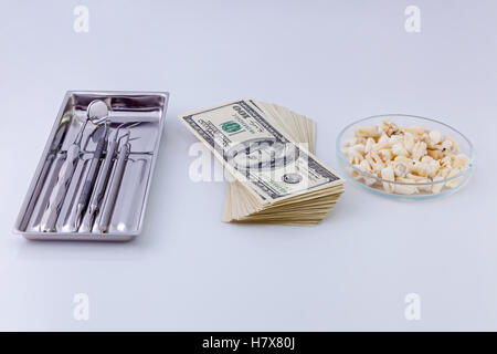 Instruments dentaires pour les dents.instruments dentaires dans le plat en argent, paquet de dollars et des dents sur une plaque en verre white Banque D'Images