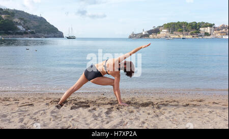 Une femme pratiquant le yoga sur une plage de Majorque. Poser l'angle de côté 2 illustré Banque D'Images