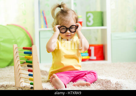 Kid enfant lunettes binocle devant jouer avec abacus toy indoor Banque D'Images