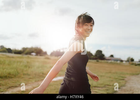 Piscine shot of young woman runner looking at camera. La Marche des femmes chinoises sur terrain en matinée.