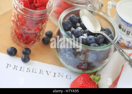 Les bleuets, framboises et fraises dans des bocaux en verre avec du sucre prêt pour faire de la confiture Banque D'Images