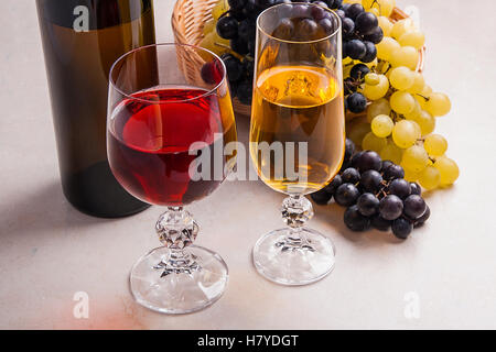 - Deux verres de vin blanc et un vin rouge et une bouteille brune avec du vin blanc sur la lumière en arrière-plan. Banque D'Images