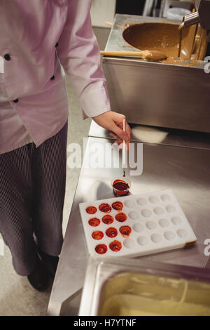 Peinture d'un travailleur à l'aide de moule chocolat chocolat de couleur Banque D'Images