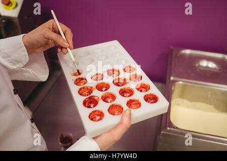 Mid section de peinture d'un travailleur à l'aide de moule chocolat chocolat de couleur Banque D'Images