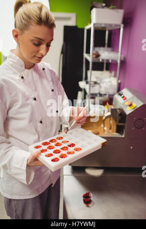 Peinture d'un travailleur à l'aide de moule chocolat chocolat de couleur Banque D'Images