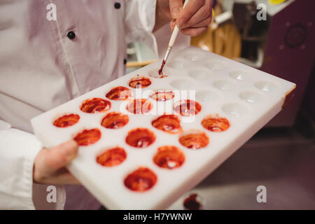 Mid section de peinture d'un travailleur à l'aide de moule chocolat chocolat de couleur Banque D'Images