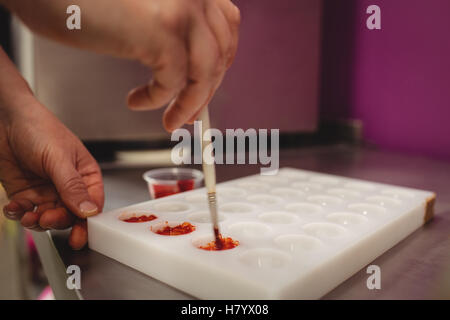 Close-up de peinture d'un travailleur à l'aide de moule à chocolat chocolat de couleur Banque D'Images