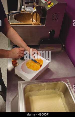 Peinture d'un travailleur à l'aide de moule chocolat chocolat de couleur Banque D'Images