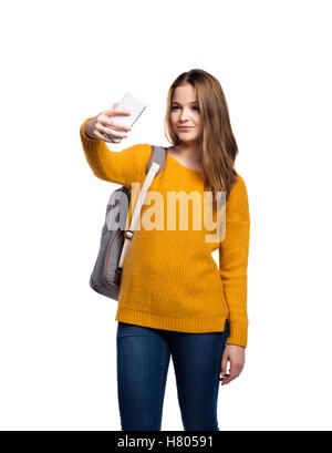 Fille en pull jaune, holding smartphone, isola, selfies Banque D'Images