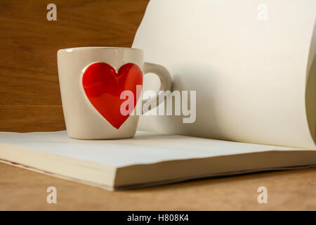 Valentines Day , tasse de café avec coeur rouge et le bloc-notes de votre texte. Vue de côté sur la table en bois,l'accent sur la coupe. Banque D'Images