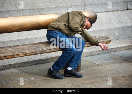 Un homme dort sur un banc à Londres Banque D'Images