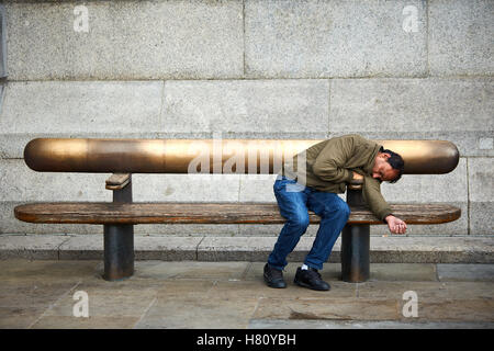 Un homme dort sur un banc à Londres Banque D'Images