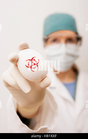 Lab technician holding egg avec bio-symbole de danger estampillée sur le document modèle libération Banque D'Images