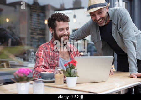 Gay couple using laptop in cafe Banque D'Images