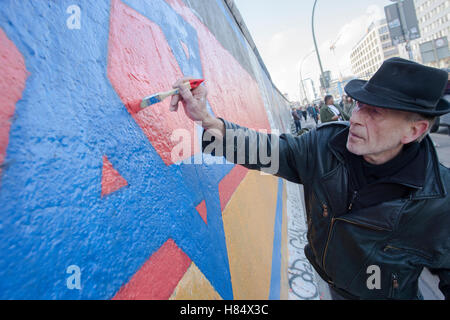 Berlin, Allemagne. 09Th Nov, 2016. Artiste Guenther Schaefer atteint pour le pinceau à la reconstruction de la pièce 'patrie' à la East Side Gallery à Berlin, Allemagne, 09 novembre 2016. Schaefer a demandé à l'action pour l'anniversaire de l'ouverture du Mur de Berlin. Dans le passé, beaucoup de visiteurs à l'East Side Gallery griffonné à l'œuvre. Photo : PAUL ZINEKN/dpa/Alamy Live News Banque D'Images